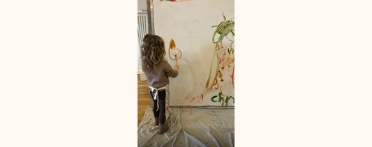 "A little girl painting on a vertical surface."