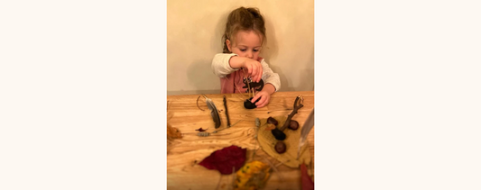 "A little girl using loose parts with playdough."