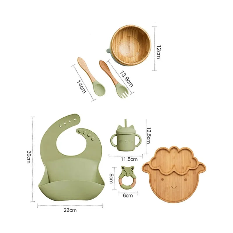 "A green and bamboo bib, rattle, cup, spoon, fork, bowl, cow shaped plate for babies and toddlers." 