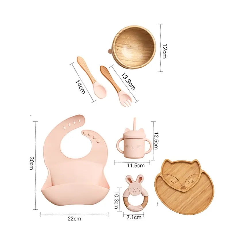 "A pink and bamboo bib, rattle, cup, spoon, fork, bowl, cat shaped plate for babies and toddlers."