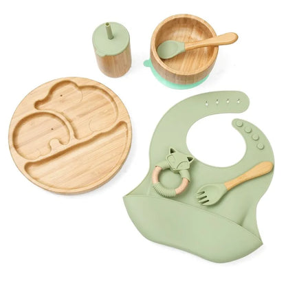 "A green and bamboo bib, beaker, cup, spoon, fork, bowl,  plate for babies and toddlers." 