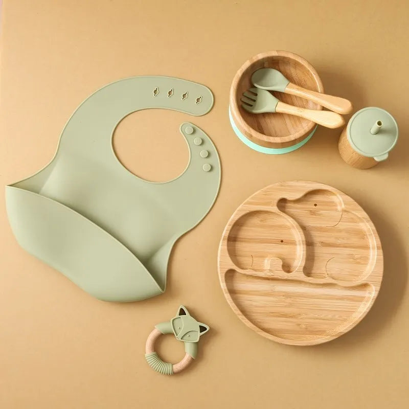 "A green and wooden bamboo feeding set for babies and toddlers."