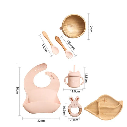 "A pink and bamboo bib, rattle, cup, spoon, fork, bowl, shell shaped plate for babies and toddlers." 