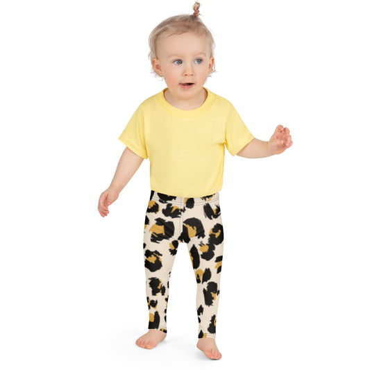 "A toddler girl wearing a yellow shirt and leopard print leggings."