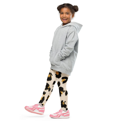 "A young girl wearing a grey hoodie and animal print leggings."