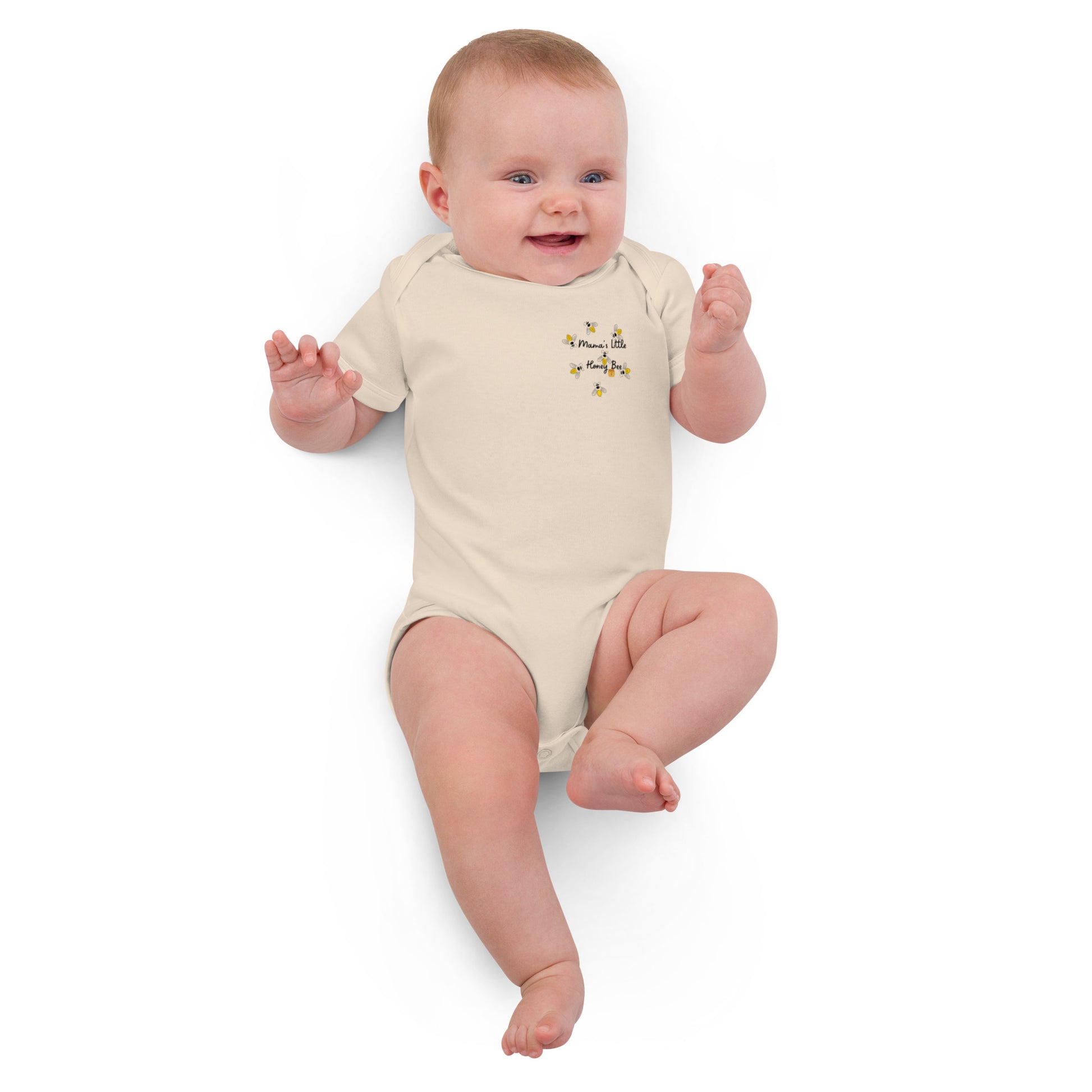 "A baby lying down laughing wearing a mamas honey bee bodysuit."