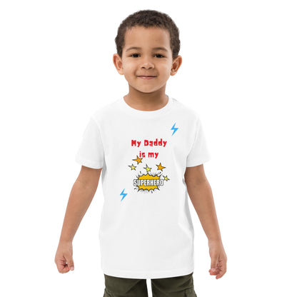 "A little boy wearing a white a my daddy is my superhero shirt."