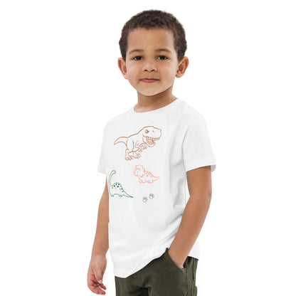 "A boy posing with his hand in his pocket wearing a white dinosaur shirt."