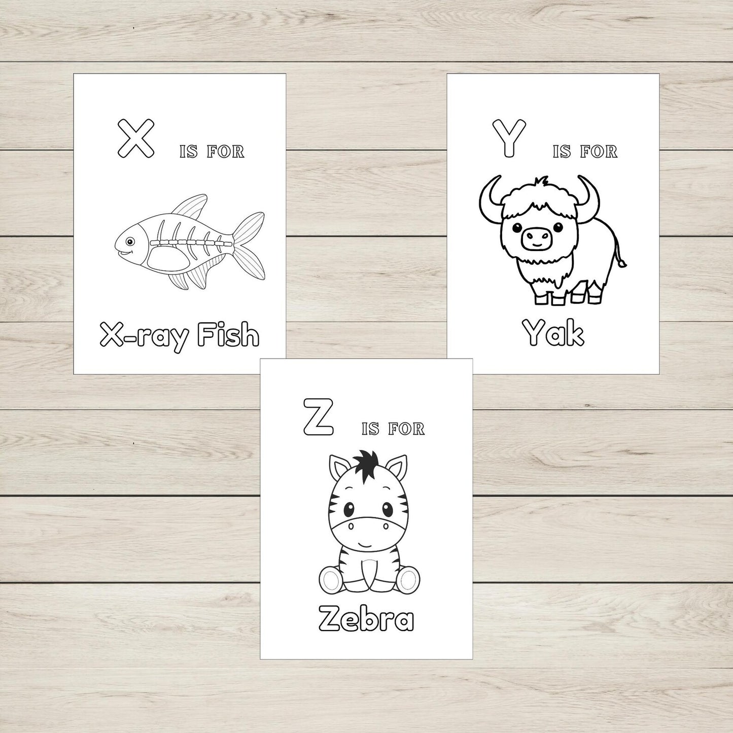 Three colouring sheets with animal illustrations and letters on a wooden surface.
