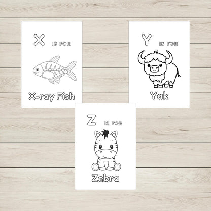 Three colouring sheets with animal illustrations and letters on a wooden surface.